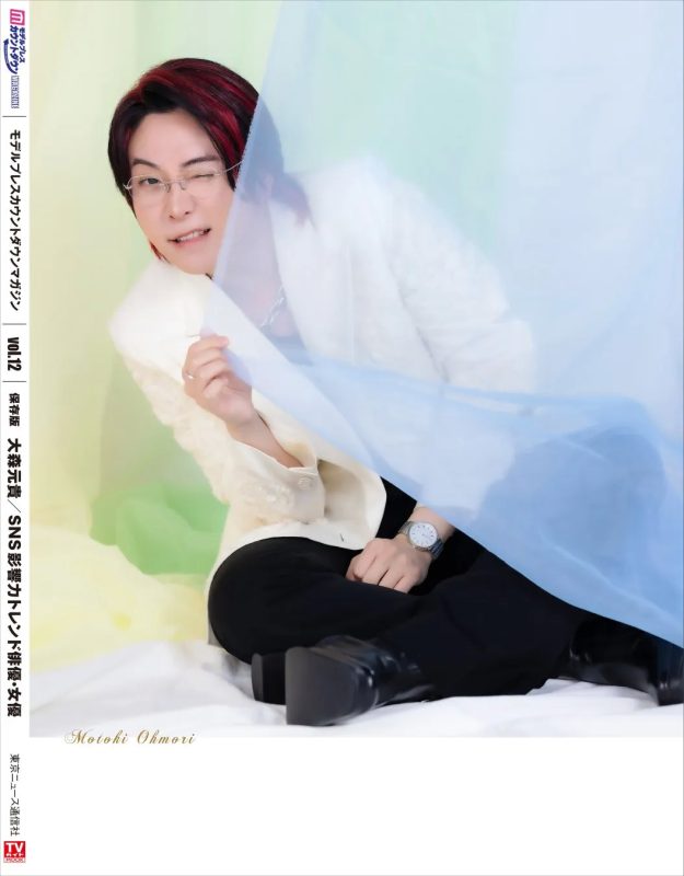 大森元貴が写った雑誌の表紙。水色の布の前に座り、ウィンクをしている。