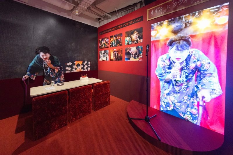カラオケルームの風景。壁には写真が飾られ、ステージには歌手の姿が映し出されている。