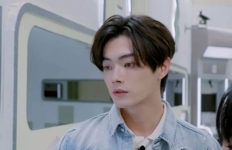 男性がカメラを見ており、薄いジーンズのジャケットを着ている。