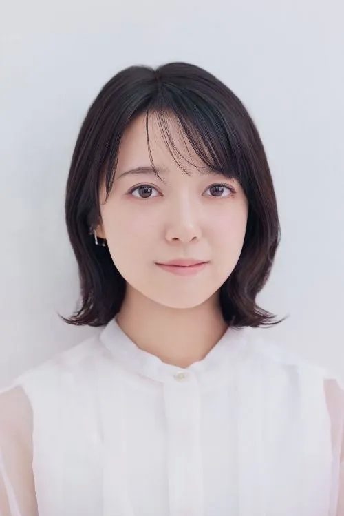 白いシャツを着た女性のポートレート。彼女は短い黒髪で、正面を見つめている。