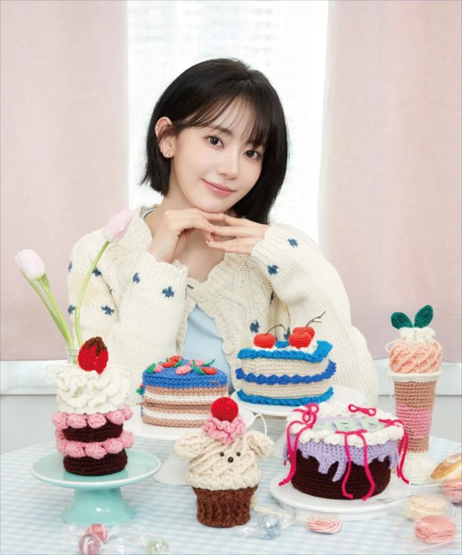 女性が手編みのケーキの前に座って微笑んでいる写真