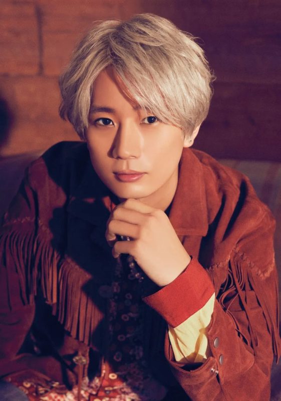 金髪の男性がカメラ目線で、顎に手を当ててポーズをとっている写真。