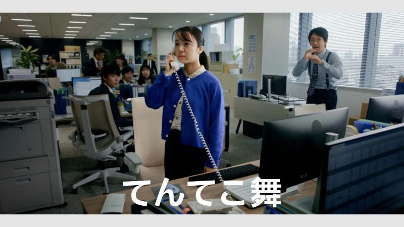 オフィスで電話をする女性と、驚いた表情の男性が描かれた写真。