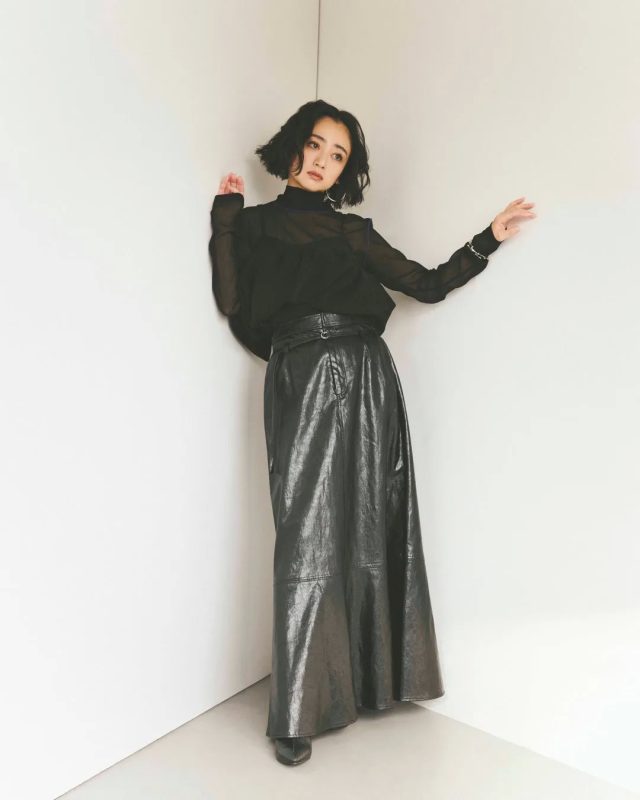 白い壁の角に寄りかかる女性のスタイリング