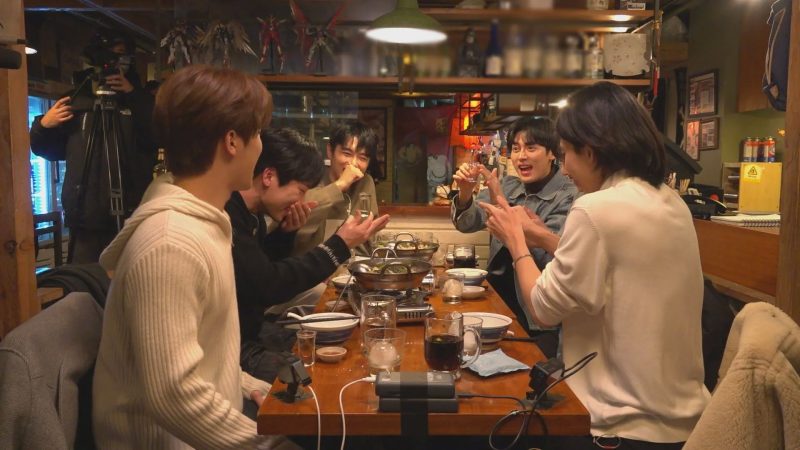 居酒屋で楽しそうに食事をする男性グループの様子を捉えた写真。彼らはテーブルを囲み、料理や飲み物を楽しんでおり、会話や笑い声が聞こえてくる様子が伝わってくる。