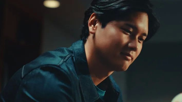 デニムジャケットを着た男性のクローズアップです。彼はカメラに微笑みかけています。