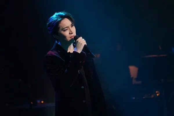 ステージでマイクを持って歌う男性の画像