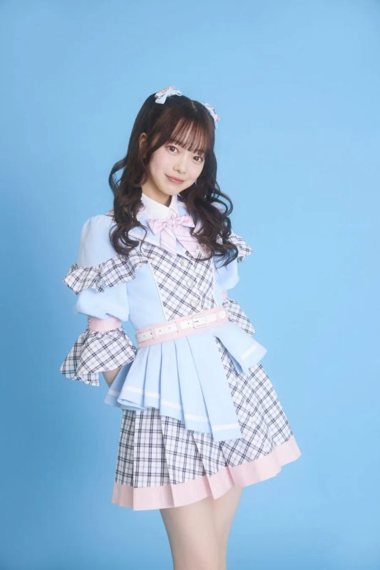 水色の衣装を着た女性のポートレート。彼女は笑顔で、背景は水色。