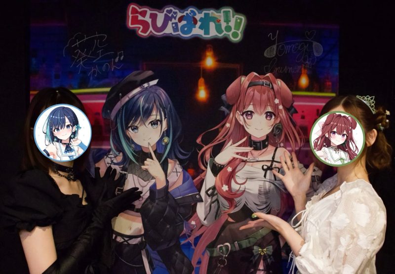 3人の女性が、背景に「らびぱれ！」のロゴと、空澄セナと音街ウナのイラストが描かれたパネルの前でポーズをとっている写真です。女性たちはパネルのキャラクターの顔が描かれた丸いステッカーで顔を隠しています。